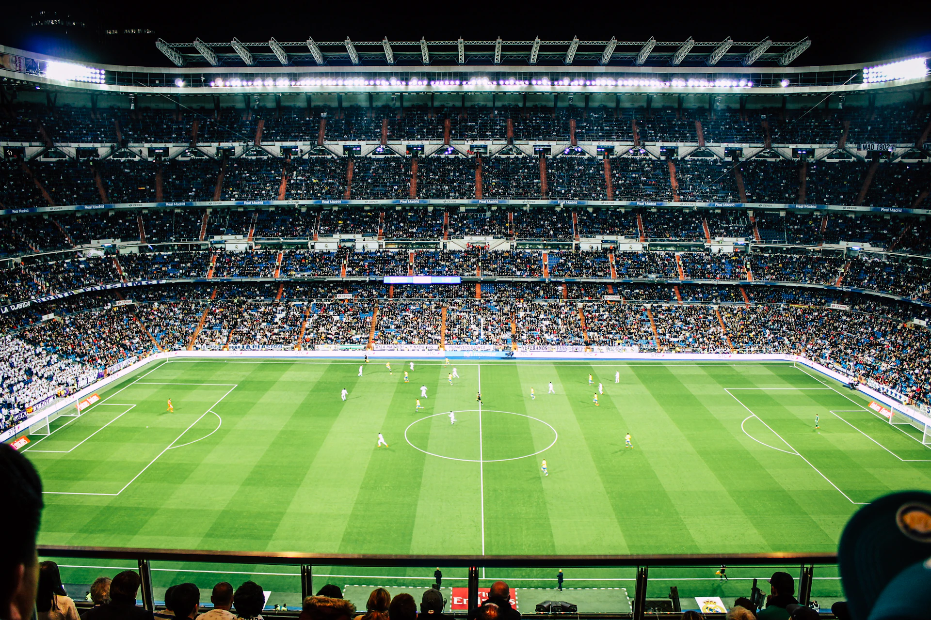 dramatic wide angle shot of a professional football stadium at night under bright stadium lights with atmospheric blue haze and smoke